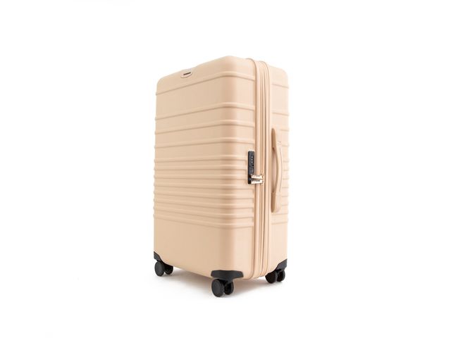 A Beis check-in roller bag in a cream color set against a white background.