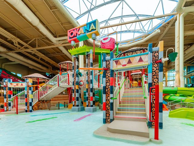 An indoor water park with a colorful play structure with water features and slides. 