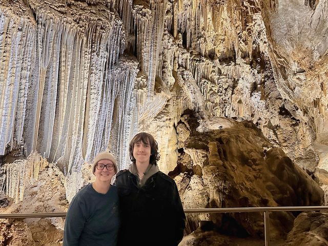 A woman and herteenage son pose in front of stalactites.