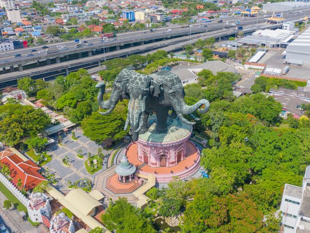 Aerial view of Erawan Museum with its elephant head sculpture with 3 heads next to leafy trees.