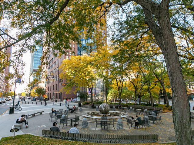 A small circular park with trees and seating in Kendall Square in Boston.