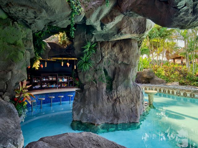 A hidden rocky grotto bar with stools for the pool inside the pool.