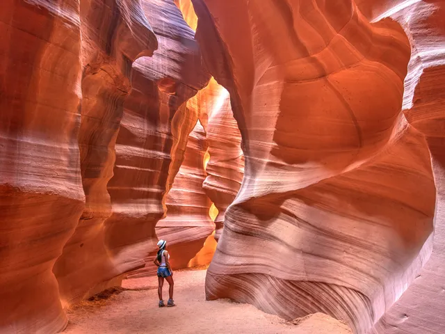 A woman hiking in a red rock slot canyon.