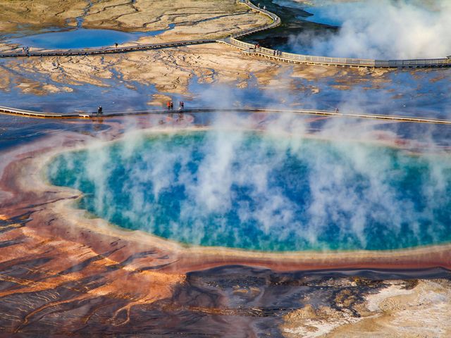 People walking on boardwalks next to steam vents and and hydrothermal areas at Yellowstone National Park