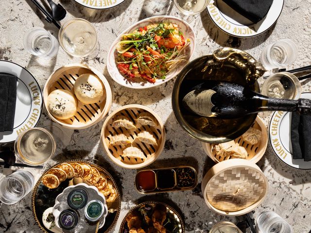 An overhead view of a lot of different dishes including dumplings and a bottle of champagne.
