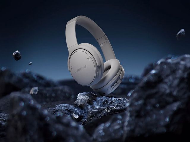 A futuristic picture of Bose Quiet Comfort Headphones against a background of black rocks.
