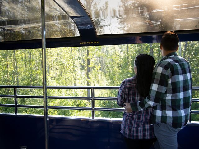 A couple embracing while looking out at trees on The GoldStar outdoor viewing deck on Alaska Railroad.
