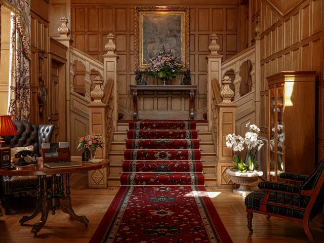 An ornate stairwell inside Glenapp Castle with carpeted steps, paneled walls, and upscale furnishings.