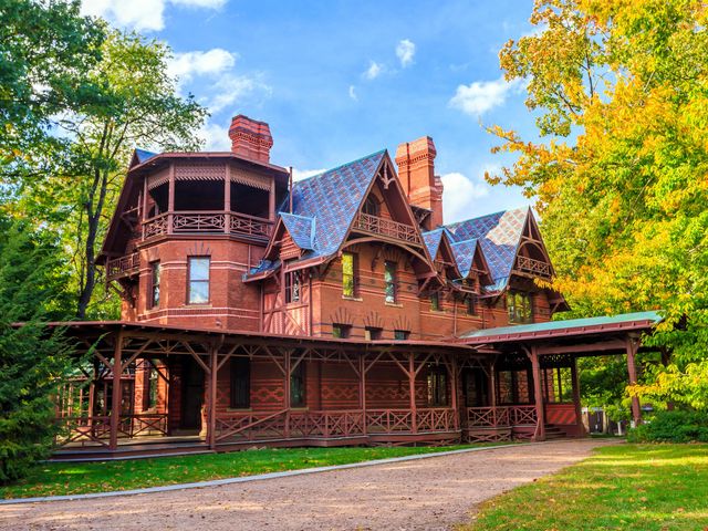 The ornate brick exterior of the Mark Twain House & Museum with a wraparound porch and decorations adorned on many bricks.