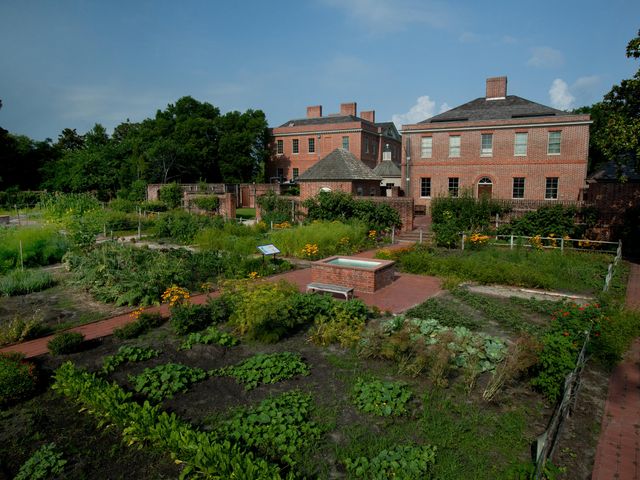 A view over Tyron Palace, a red brick building surrounded by a manicured farm.