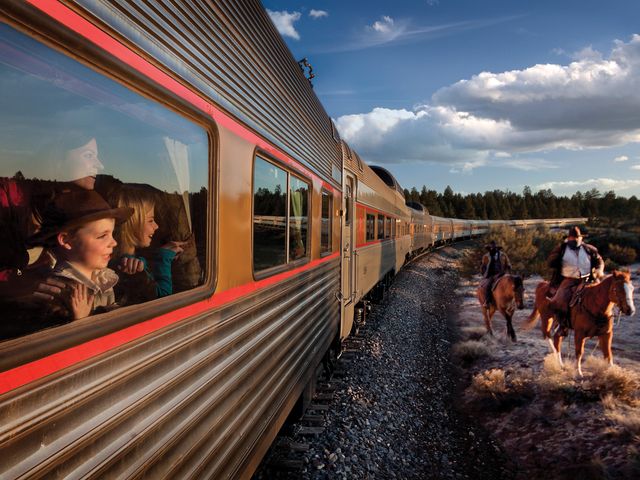 A family looking through a window on the Grand Canyon Railway with horseback riders outside.