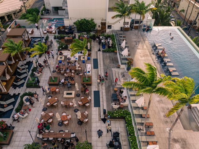 An overhead aerial view of a pooldeck with an infinity pool, dining area, cabanas, seating, and more.
