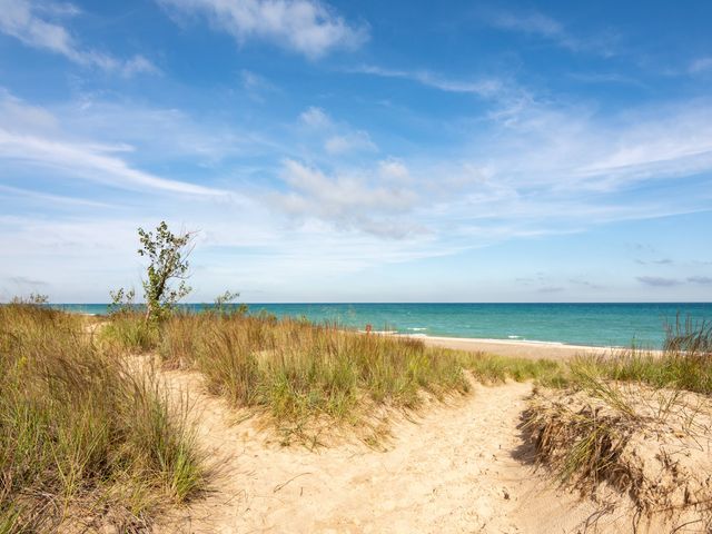 Sandy beach dunes topped with grass lead to the water at Indiana Dunes National Park.