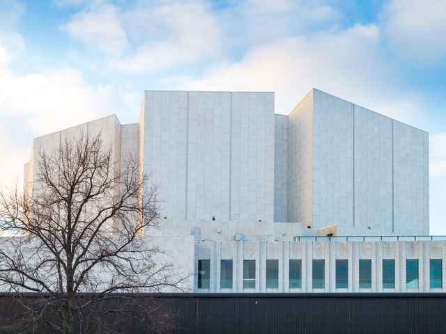 A stark white modern building with a bare tree in front.