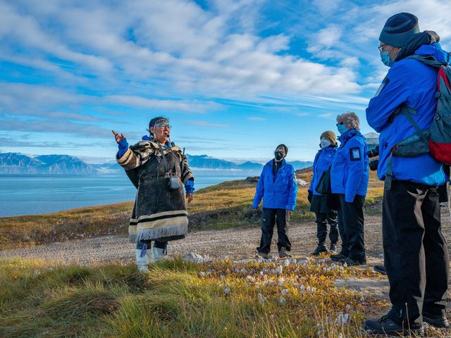 An expert speaks to a group of people in front of the water.