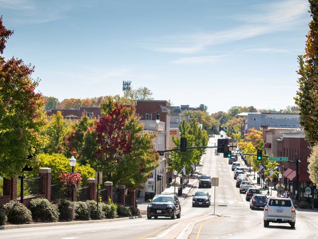 A street in downtown Blacksburg with low-rise buildings and trees with leaves of different colors.