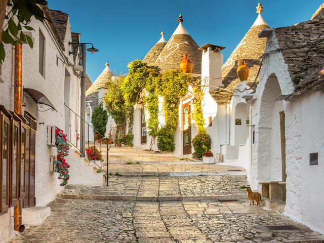 Limestone thatched roof huts lining a cobblestone street in Puglia, Italy.
