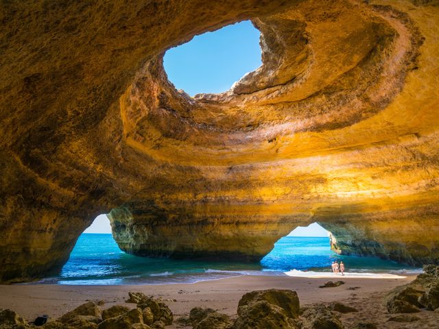 Inside a seaside cave with holes on top and two on the side letting seawater and sunlight in.
