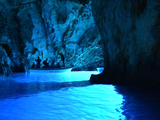 Inside a cave with water that is glowing bright blue.