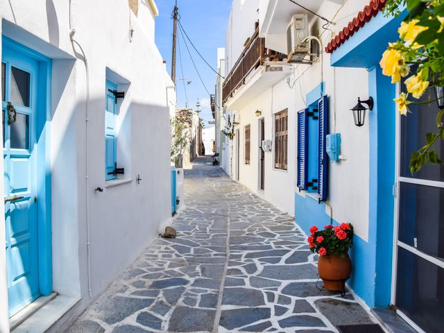 A village on Naxos with a stone alleyway, white buildings, and blue trim doors and windows.