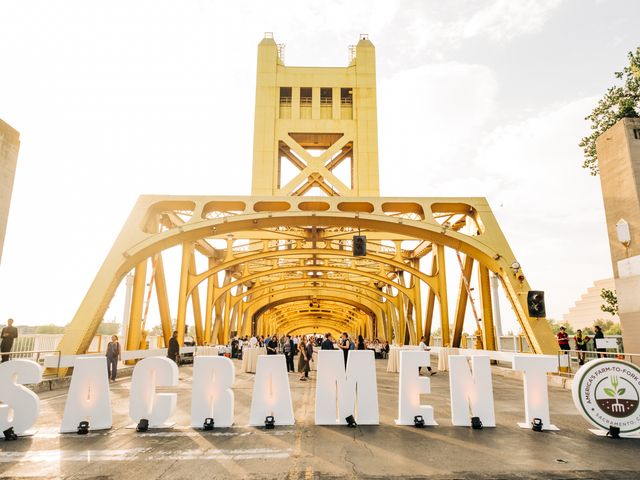 A yellow bridge is closed to traffic with people gathered inside for a meal and giant letters that spell out Sacramento.