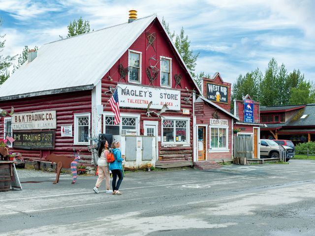 The Talkeetna General Store, with a red and white exterior and people walking in front.