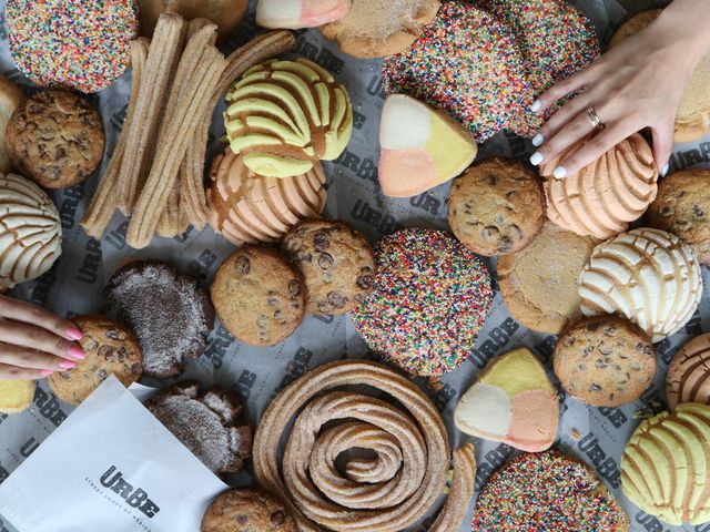 An overhead view of hands reaching for an assortment of Mexican pastries.