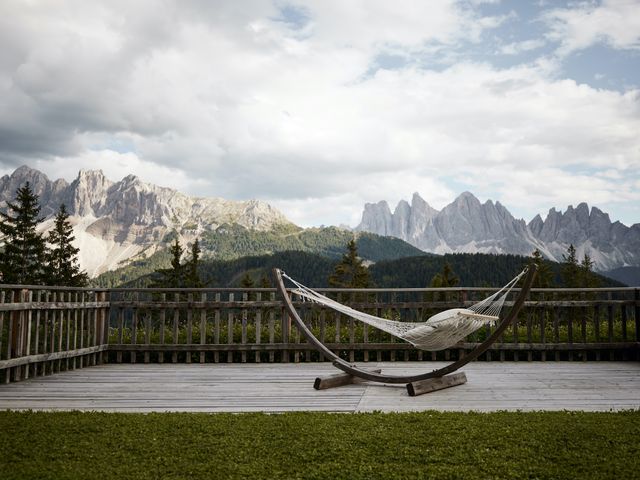 An empty hammock set on a deck facing views of the Dolomite mountains in Italy.