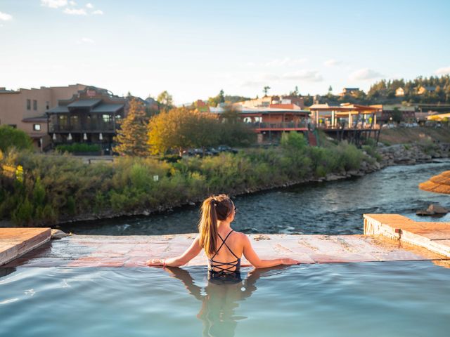 A woman with a pony tail overlooking the edge of an infinity pool.