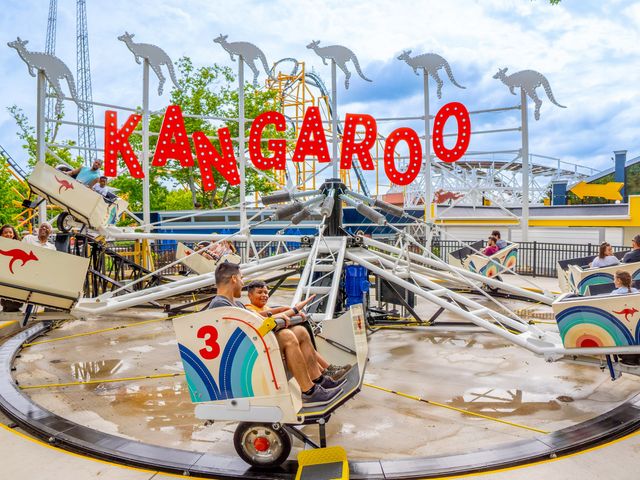 An adult man and child ride in a colorful cart on the Kangaroo carnival ride at Kennywood Amusement Park