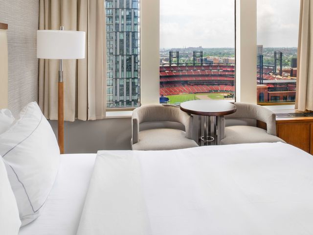 A hotel room with a large bed next to windows with direct baseball stadium views.