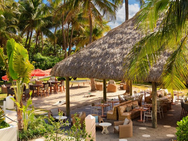 An aerial view over the beach club at Kimpton Surfcomber with a thatched hut bar and seating areas.