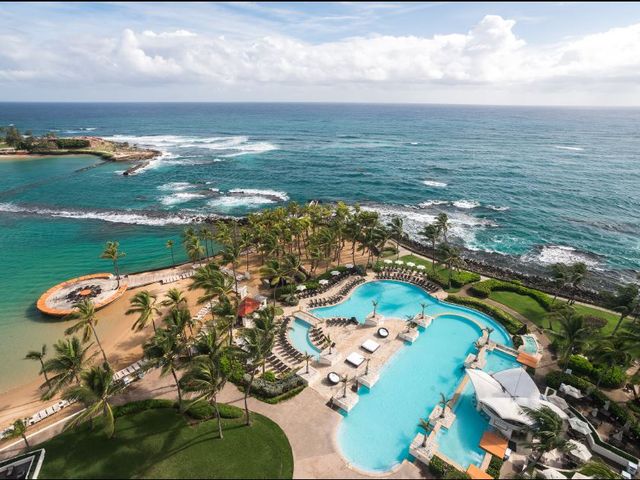 An overhead aerial view of Caribe Hilton with views of the pool next to the beach and ocean.