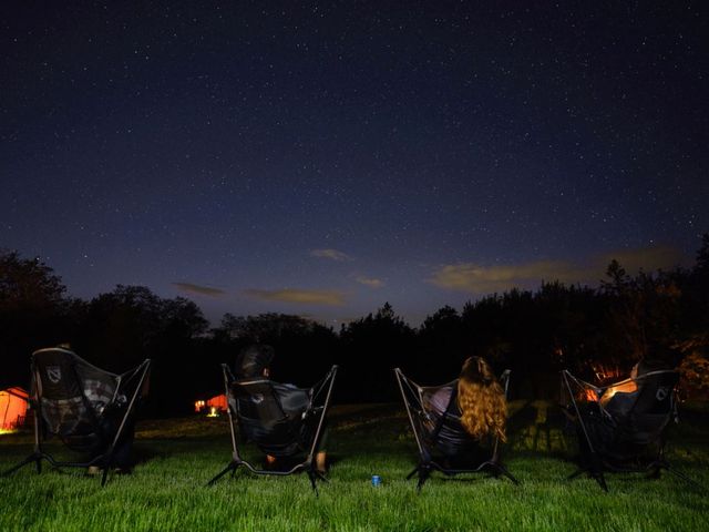 People sit in chairs at night next to a fire and admire the night sky.