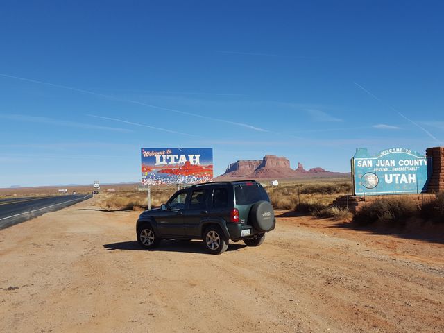 A car on the side of the road next to a welcome to utah sign.