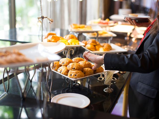 A hotel buffet breakfast line with a hand visible reaching for a chocolate croissant.