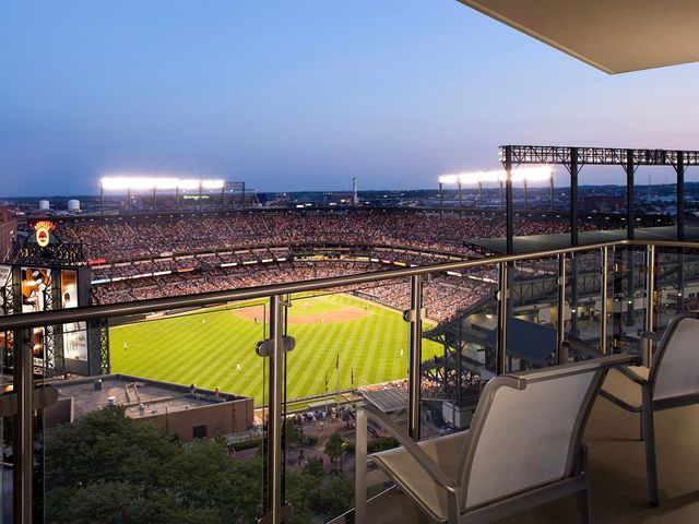 A view of a baseball stadium from a balcony suite with two chairs facing the field at night.