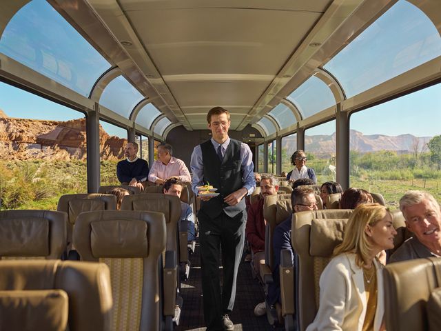 A staff member serving good inside the domed window car onboard Canyon Spirit's Rockies to Red Rocks route.