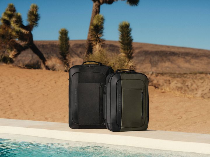 Two backpacks sit on the edge of a pool in the desert.