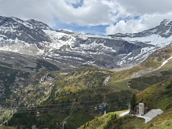 A view of Hintertux Glacier in Austria with snow-capped mountains on top and greenery down below.