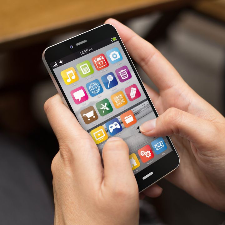 Hands holding a smartphone with apps showing.