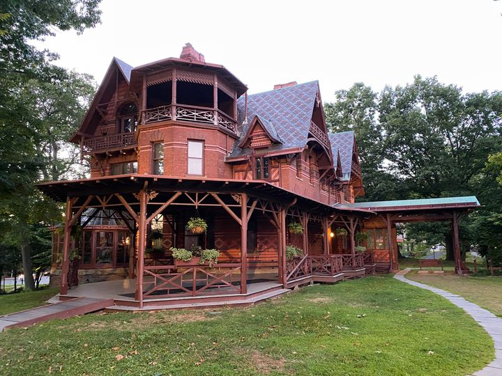 The red brick exterior of the Mark Twain House & Museum with a wraparound porch and arched Victorian-style roof.