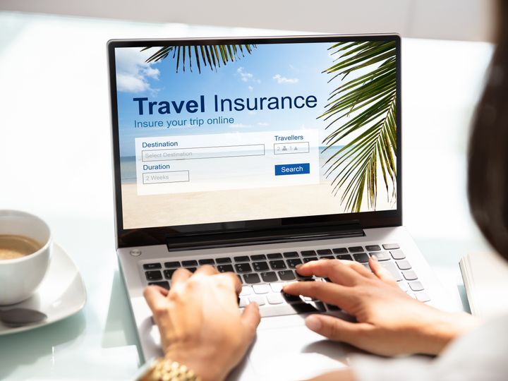 Hands typing on a laptop with the screen showing a Travel Insurance inquiry form.