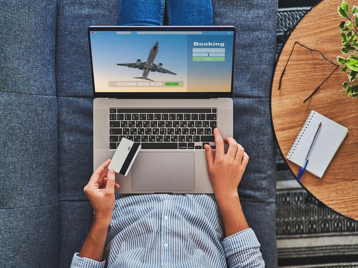 Overhead shot of someone buying plane tickets using a computer and credit card.