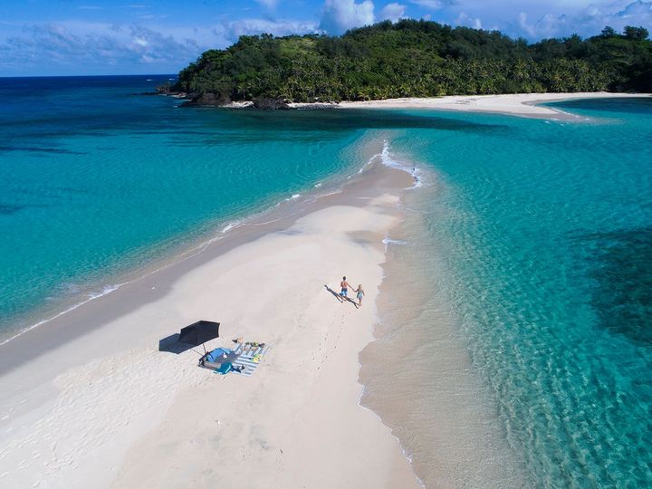 A sandbar stretch of sand between turquoise water leading to a small island at Yasawa Island Resort.