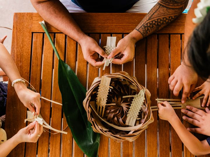Hands are seen from overhead taking part in a weaving class at Outrigger Ka'anapali Beach Resort.
