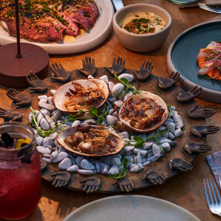 An overhead shot of a table filled with glasses and dishes of food with a circular dish in the middle.