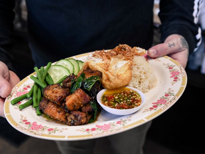 Hands serving a dish of food at Eem in Portland, Oregon.
