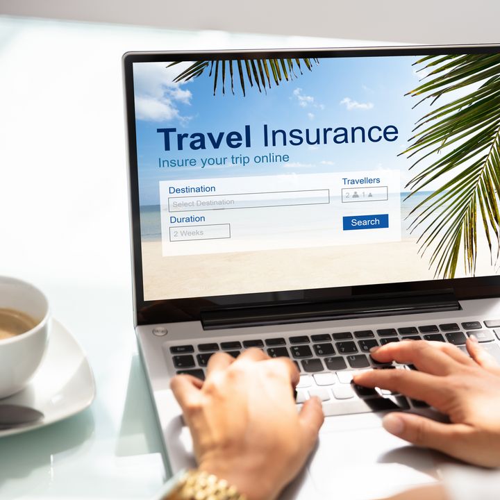 Hands typing on a laptop with the screen showing a Travel Insurance inquiry form.