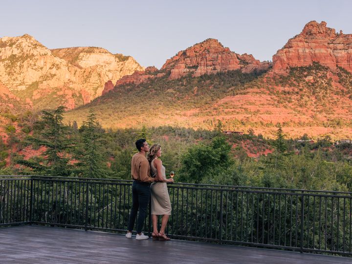 A man and a woman embracing while taking in views on a deck facing Sedona’s scenic red rock formations.